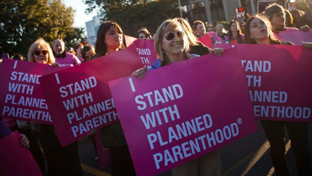 Supporters of Planned Parenthood hold signs at a rally. Source: Getty Images