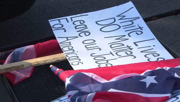 Signs read "White lives do matter. Leave our jobs for Americans," (far right of image) "Wake up White America. Your history is being hidden or erased," pictured with Confederate. Ku Klux Klan rally in Anaheim, Ca